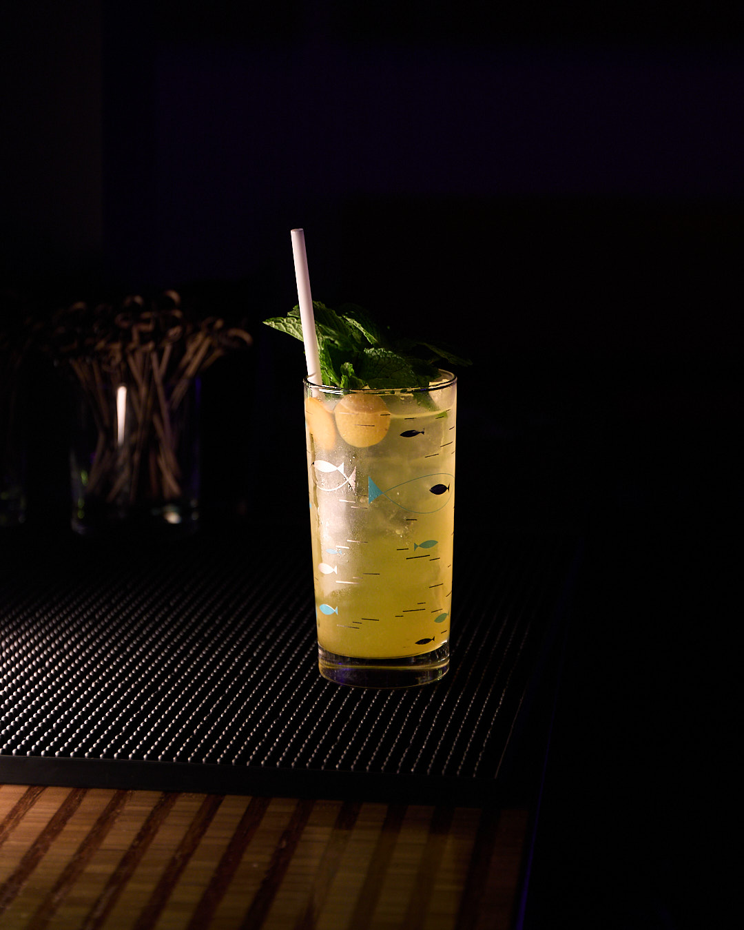 A tall glass of Harvey Wallbanger cocktail with mint and a straw, sitting on a bar.